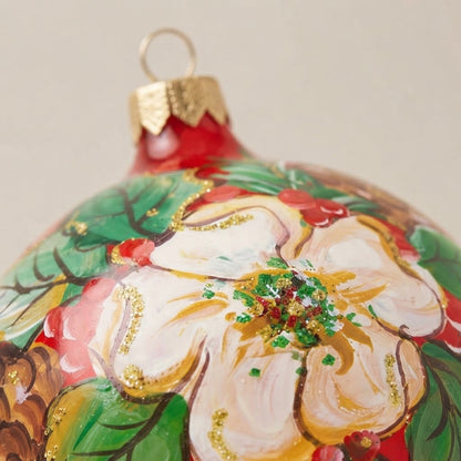 Dettaglio del decoro dipinto a pennello: fiore bianco, pigne e agrifoglio su fondo rosso