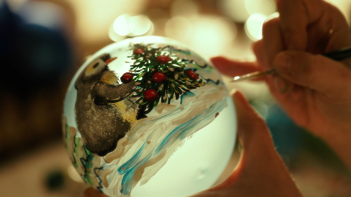 Decoratrice che dipinge a mano una palla di Natale in vetro nel laboratorio di Bellagio