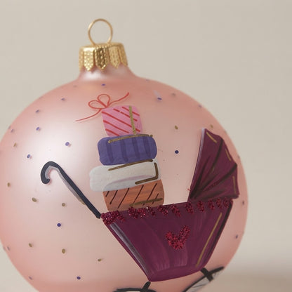 Close-up of the brush-painted decoration: Christmas ornament with baby carriage and gifts on pink