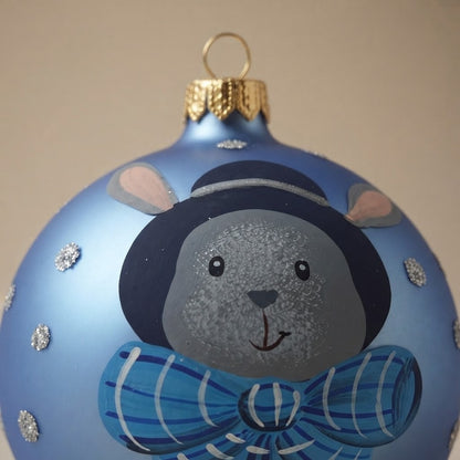 Close-up of the brush-painted decoration: Christmas ornament with bunny in hat and bow on blue