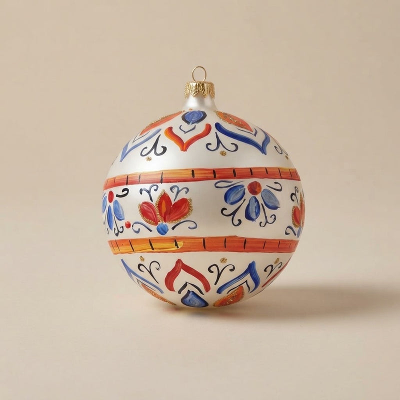 Palla di Natale Ø 10 cm dipinta a mano in stile maiolica: fasce arancio, fiori rossi e foglie blu su fondo bianco