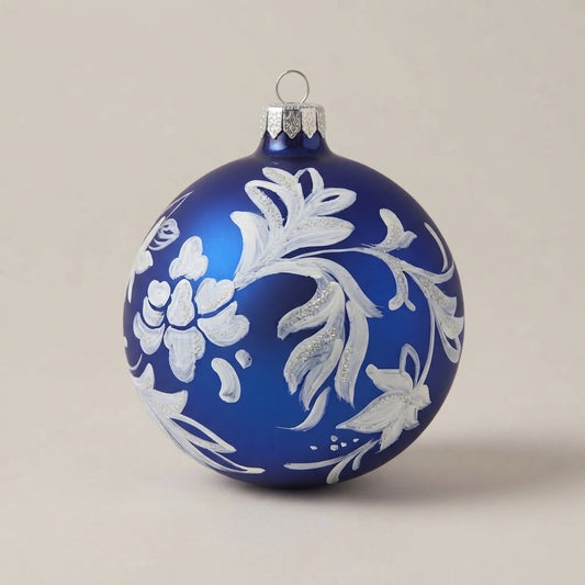 Palla di Natale Ø 10 cm dipinta a mano in stile maiolica: tralcio di fiori e foglie bianche su fondo blu opaco