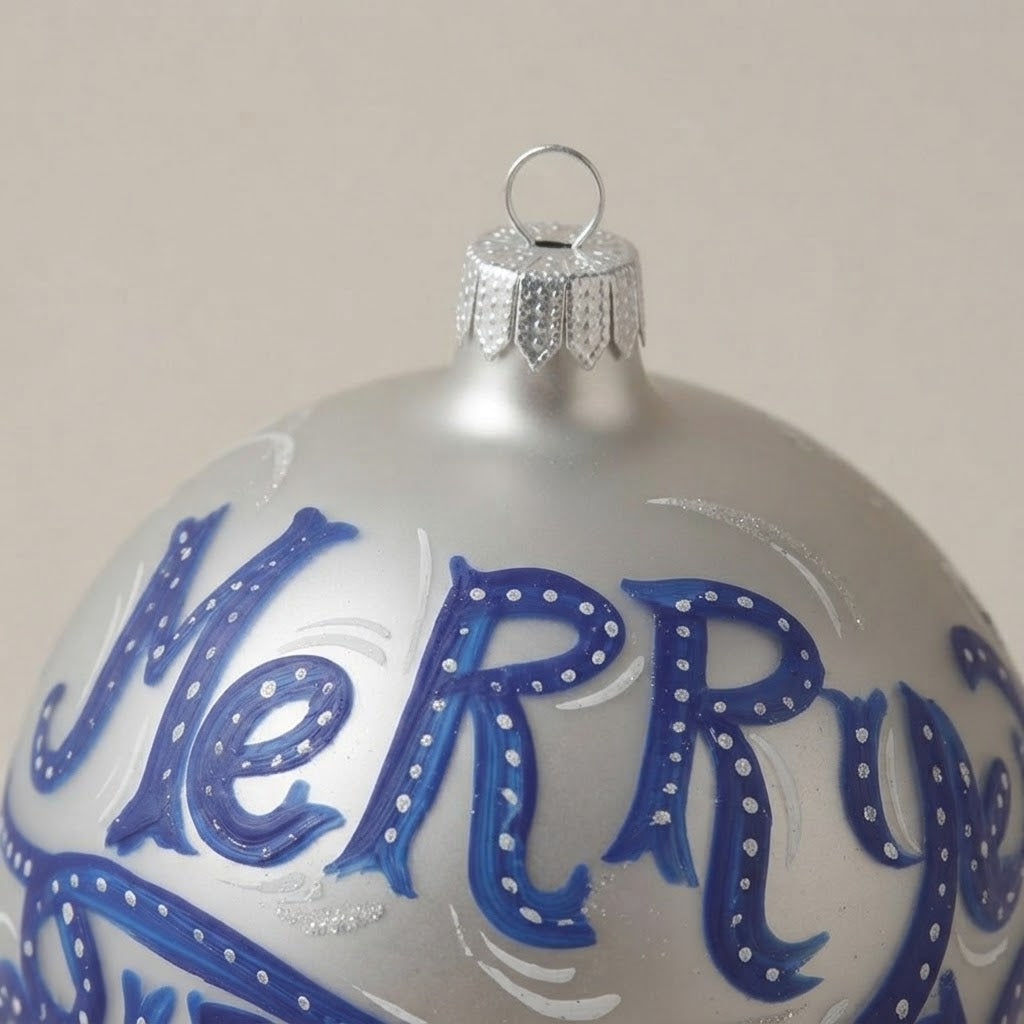 Dettaglio del decoro dipinto a pennello: scritta Merry Christmas blu su argento