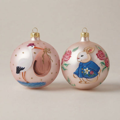 Set da 2 palle di Natale con una cicogna e un coniglietto su fondo rosa, dipinte a mano
