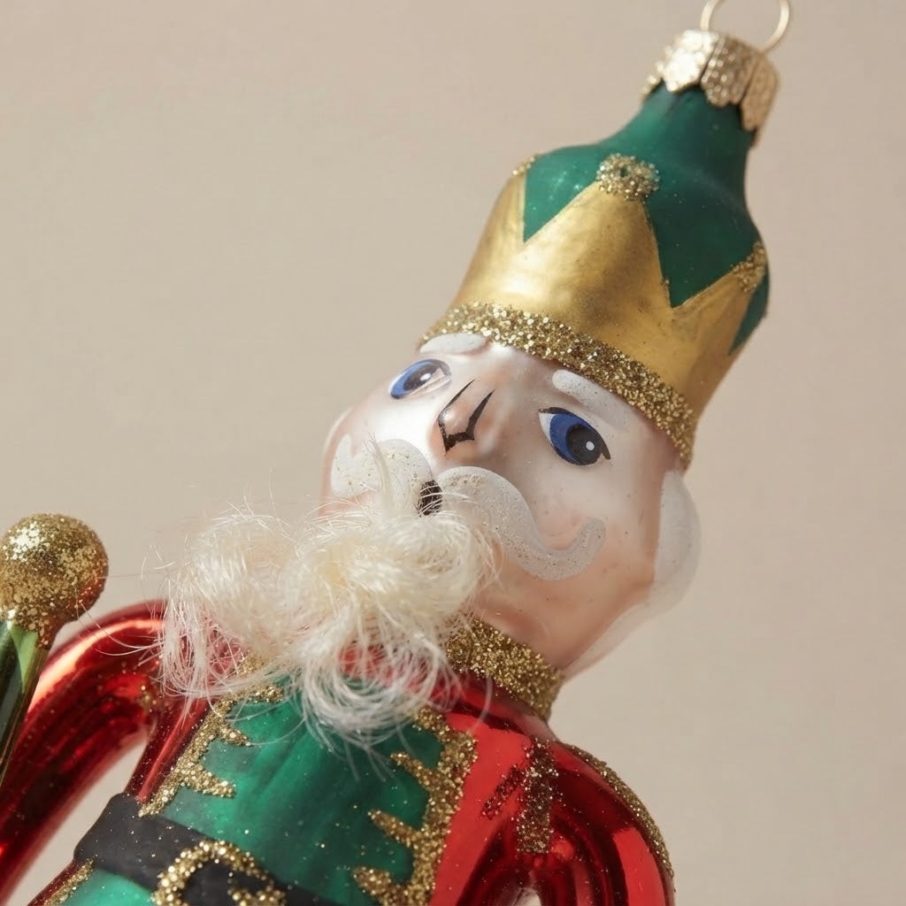 Dettaglio del volto dello schiaccianoci: corona verde e oro, occhi azzurri e barba bianca