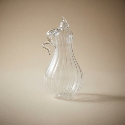 Clear glass pear-shaped pumpkin on a warm background
